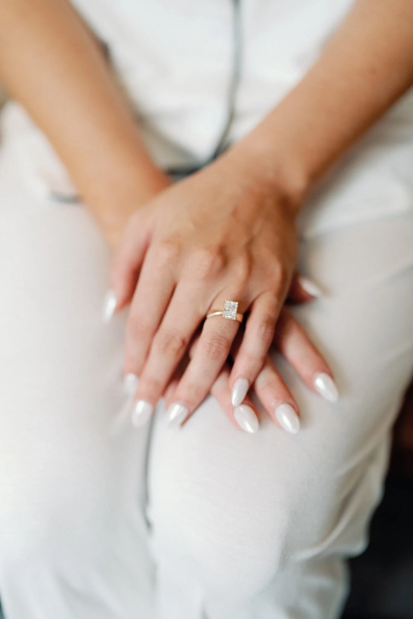 Emerald-cut engagement ring on the bride's folded hands as she gets ready