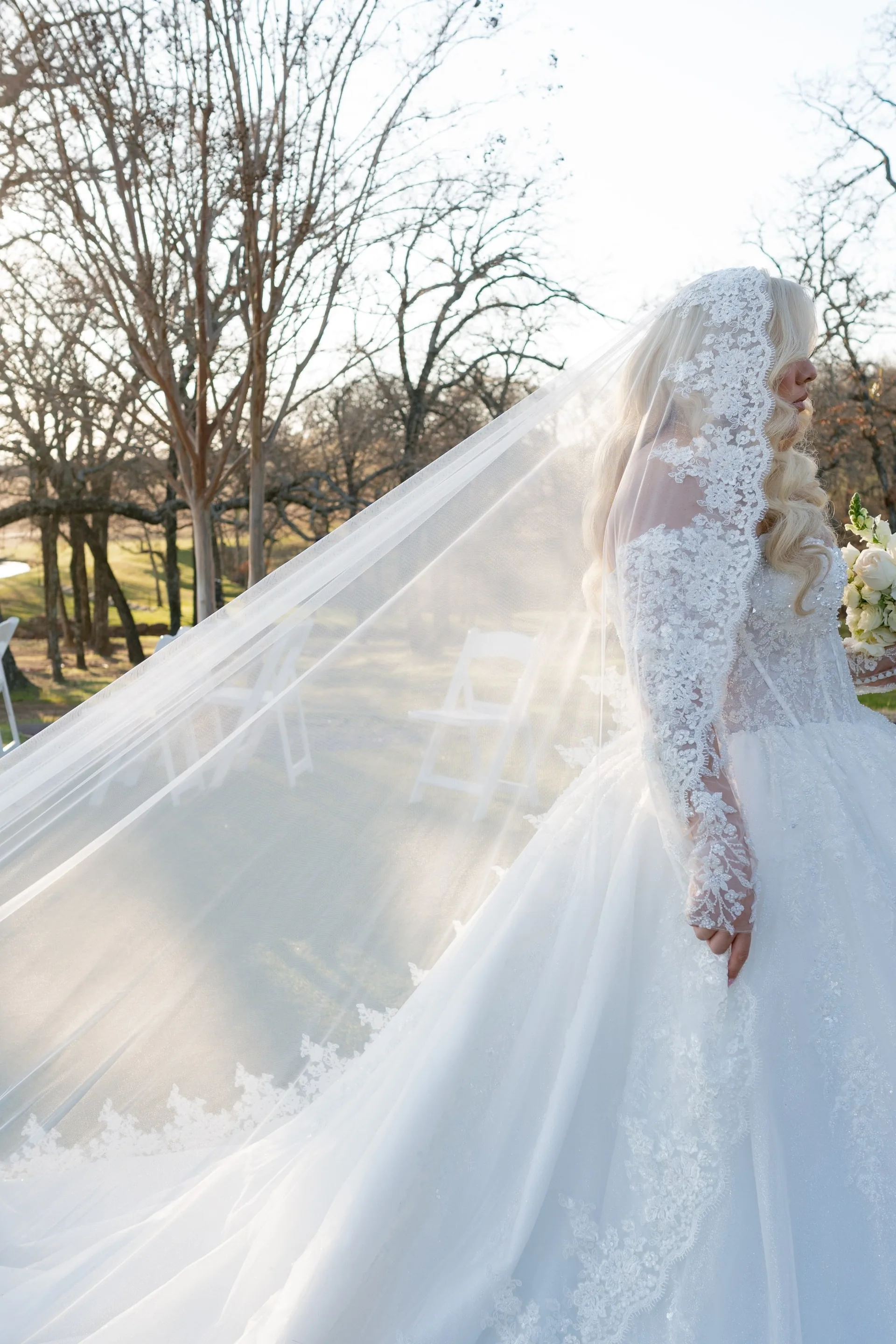 Cathedral veil sweeping through winter light as the bride stands at her outdoor ceremony