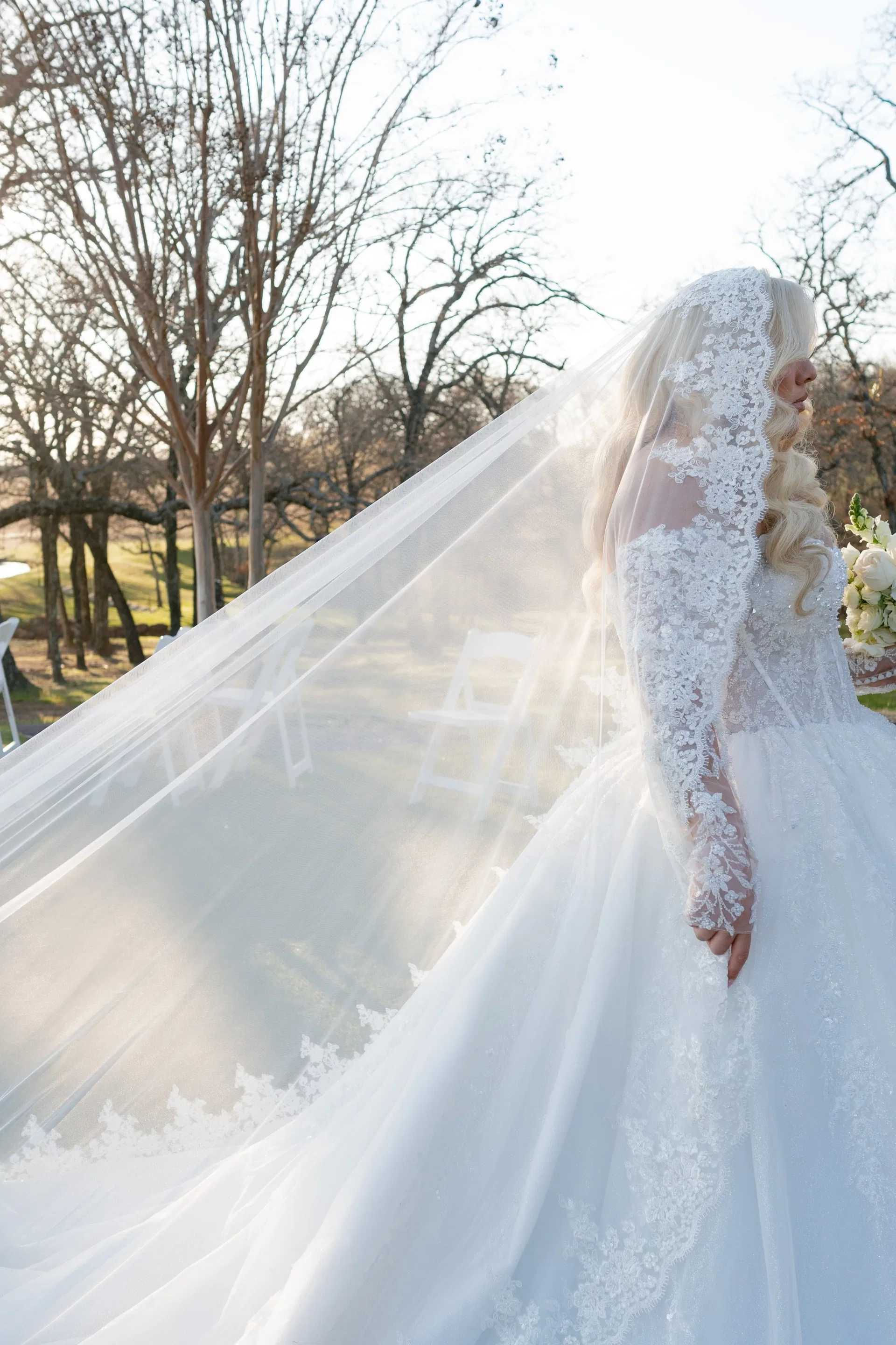 Bride's lace-edged cathedral veil catching sunlight before an outdoor winter ceremony